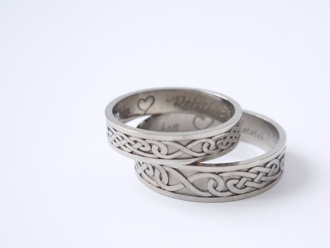White gold wedding rings with a celtic knotwork on the outside.